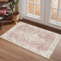 a pink and white area rug in front of a wooden door with potted plant