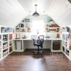 a home office with white shelving and wood flooring in an atticed room