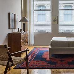 a bed sitting in the middle of a living room next to a chair and window