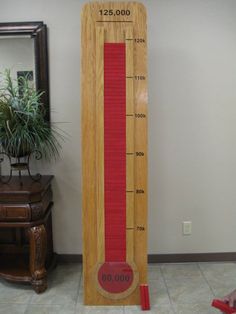 a tall wooden thermometer sitting on top of a floor next to a mirror