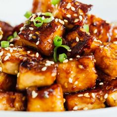 tofu with sesame seeds and green onions on a white plate