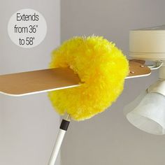 a yellow duster sitting on top of a white table next to a light fixture