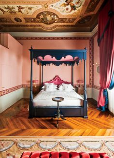 a bed sitting in the middle of a room with pink walls and wooden flooring