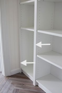 an empty white book shelf with two arrows pointing to the left and right ends, in a room with wood flooring