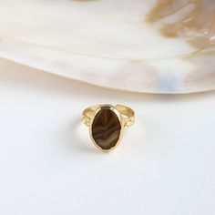 Adorn your finger with Brown Agate Ring. Handcrafted from copper and plated with 24k gold, it embodies timeless beauty. Embrace elegance with this unique, artisanal accessory that adds a touch of sophistication to your ensemble. Details: Materials: Copper, 24K Gold Plated, Agate Size: adjustable from 6 to 8 ring sizes. Nickel Free Important info: Please note that our collection is meticulously curated by a diverse array of makers and designers within friends. Be aware that for certain items, we Gold Rings With Natural Stones For Gift, Gold Open Ring With Natural Stones, Elegant Gold Crystal Ring With Cabochon, Spiritual Gold Rings With Natural Stones, Elegant Adjustable Agate Rings, Elegant Agate Open Ring, Gold Brass Crystal Ring With Gemstone, Gold Crystal Ring With Natural Stones, Elegant Brown Rings With Natural Stones