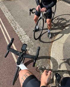 two bicyclists are riding down the street with their bikes in front of them