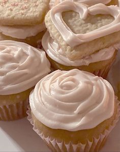 cupcakes with white frosting and hearts on them are arranged in a heart shape