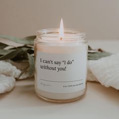 a candle sitting on top of a table next to some white towels and green leaves