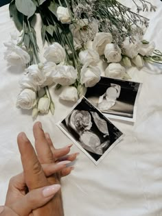 two hands touching each other on a table with flowers and pictures next to it,