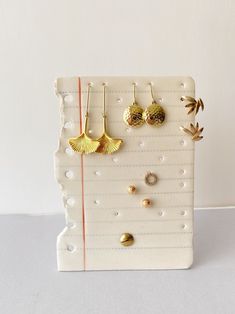 three pairs of earrings are hanging on a white board with pins and hooks in the shape of seashells