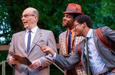 three men in suits and ties are standing next to each other while one man is holding a clipboard