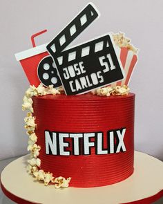 a red cake with popcorn and claps on top that says netflix next to it