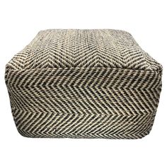 a black and white chevroned ottoman with an upholstered cushion on top