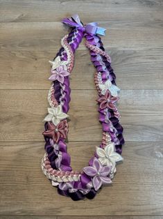 a purple and white necklace with flowers on it sitting on top of a wooden floor