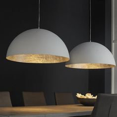 two lights hanging over a dining table with chairs and a bowl of food on it