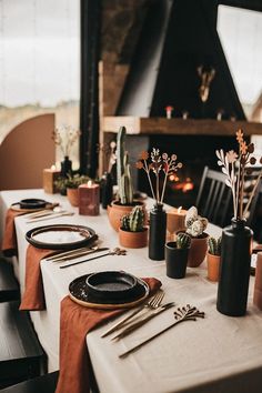 the table is set with black and white plates, utensils and succulents