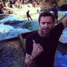 a man giving the thumbs up while standing in front of a river filled with people