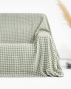 a green and white checkered couch sitting next to a plant on top of a table