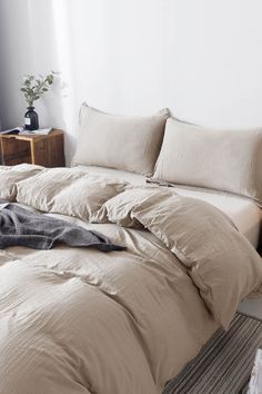 an unmade bed in a white room with pillows and blankets on top of it