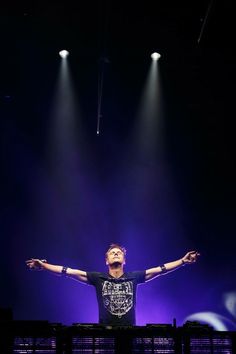 a man standing on top of a stage with his arms outstretched in front of him