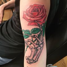 a person with a tattoo on their arm holding a rose