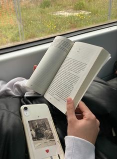 someone is reading a book in the back seat of a car while holding an iphone