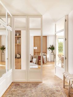 the interior of a house with white walls and wood flooring, large mirror on the wall