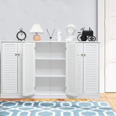 a white cabinet sitting on top of a wooden floor next to a blue and white rug