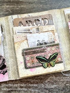 an altered book is open to show the inside pages and features stamps, papers, scissors, and other things