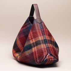 a red and blue plaid handbag on a white background with a wooden handle in the middle