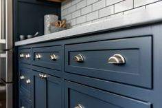 a kitchen with blue cabinets and white subway backsplash, stainless steel counter tops