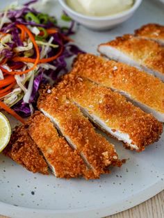 a white plate topped with sliced chicken next to a salad