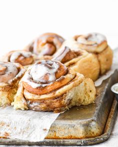 cinnamon rolls with icing sitting on top of a cutting board