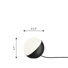 a black and white ball sitting on top of a table next to a measuring line