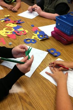 children sitting at a table with scissors and paper cut out to look like numbers on them