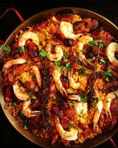 a pan filled with shrimp and rice covered in garnish