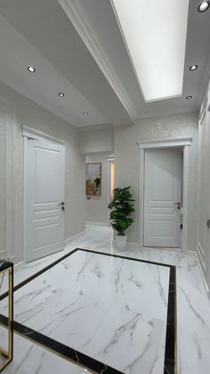 an empty room with marble floors and white walls, along with two planters on either side of the door