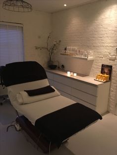 a white and black bed in a room next to a counter with candles on it