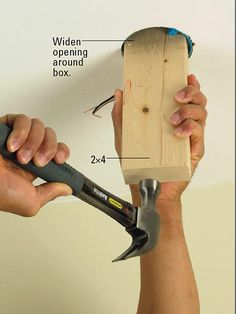 a person holding a hammer and pliers in front of a wooden board with measurements on it