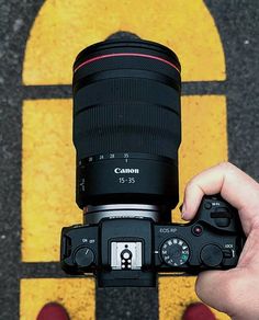 a person holding up a camera in front of a yellow door