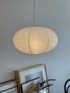 a white light hanging from the ceiling above a table with pictures and framed objects on it