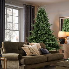 a living room filled with furniture and a green christmas tree in the middle of it