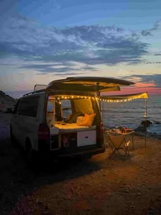 a van parked on the beach with its lights on and it's door open