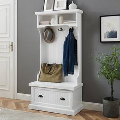 a white coat rack with two coats hanging on it's sides and a purse next to it