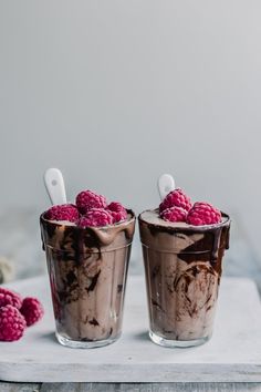 two glasses filled with ice cream and raspberries