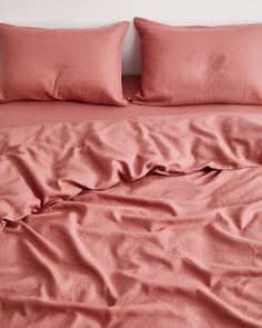 an unmade bed with pink sheets and pillows