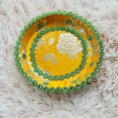 a yellow and green plate with beads on it sitting on a white furnishing