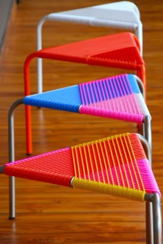 three colorful chairs sitting on top of a wooden floor