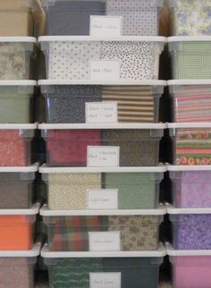 many different types of fabric are stacked in bins with labels on the bottom and bottom