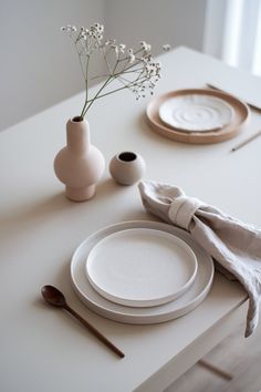 the table is set with plates, napkins and flowers in a vase on it